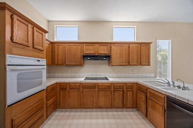 7507 N Constance Ave, Fresno, CA 93722 - kitchen featuring white oven, dishwasher, light flooring, under cabinet range hood, and brown cabinets