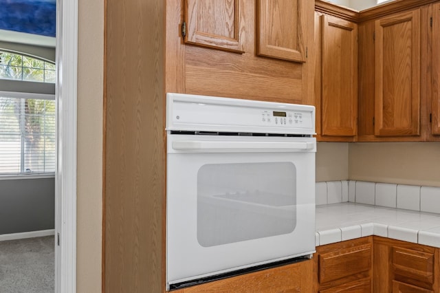 7507 N Constance Ave, Fresno, CA 93722 - kitchen featuring white oven, brown cabinets, and carpet
