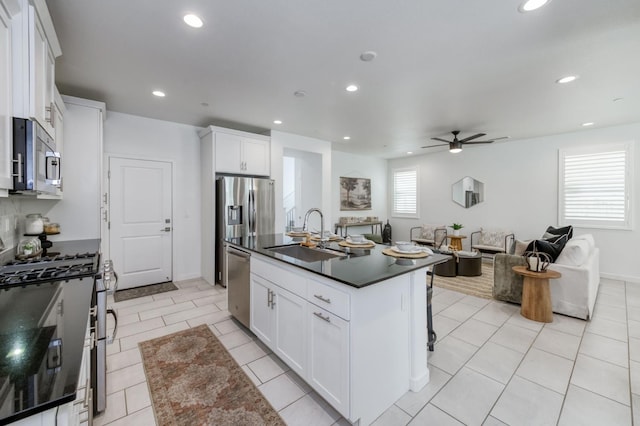4670 Terrace Rd, Madera, CA 93636 - kitchen with appliances with stainless steel finishes, dark countertops, a ceiling fan, white cabinets, and a kitchen island with sink