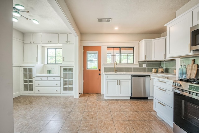 730 E Yale Ave, Fresno, CA 93704 - kitchen with stainless steel appliances, light countertops, plenty of natural light, white cabinets, and a textured ceiling