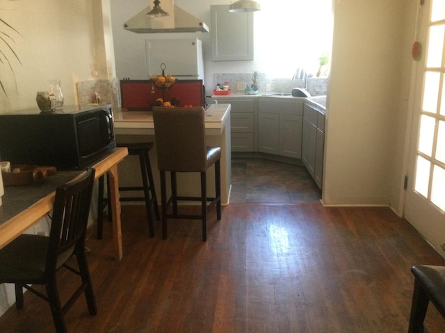 411 E Fountain Way, Fresno, CA 93704 - kitchen with refrigerator, black microwave, dark wood-style flooring, light countertops, and a kitchen breakfast bar