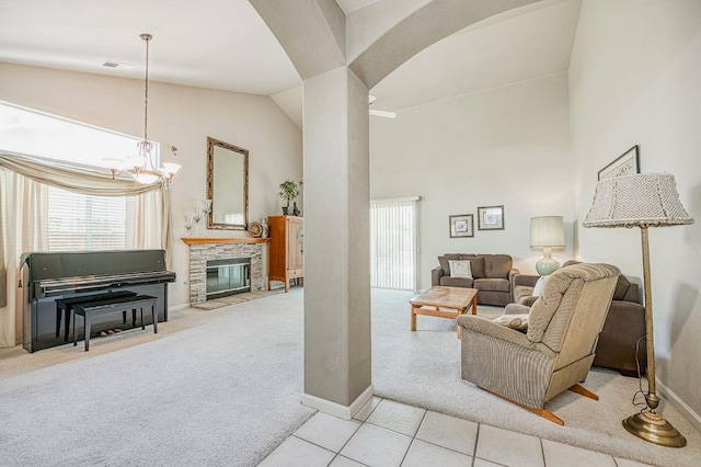 2869 E Brandon Ln, Fresno, CA 93720 - carpeted living area with high vaulted ceiling, a chandelier, arched walkways, a stone fireplace, and tile patterned flooring