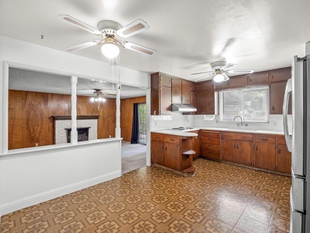 4629 N Fisher St, Fresno, CA 93726 - kitchen featuring under cabinet range hood, ceiling fan, freestanding refrigerator, healthy amount of natural light, and wood walls