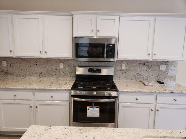 3869 Griffith Ave, Clovis, CA 93619 - kitchen with appliances with stainless steel finishes, white cabinets, tasteful backsplash, and light stone counters