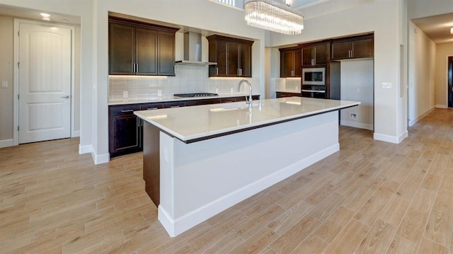 925 Talus Way S, Madera, CA 93636 - kitchen featuring wall chimney exhaust hood, appliances with stainless steel finishes, light wood-style floors, and decorative backsplash