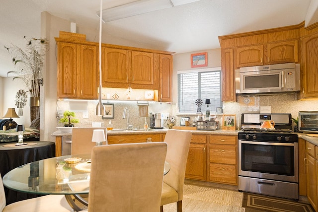 51 E Tuolumne St, Fresno, CA 93706 - kitchen with stainless steel appliances, tasteful backsplash, light countertops, and brown cabinetry
