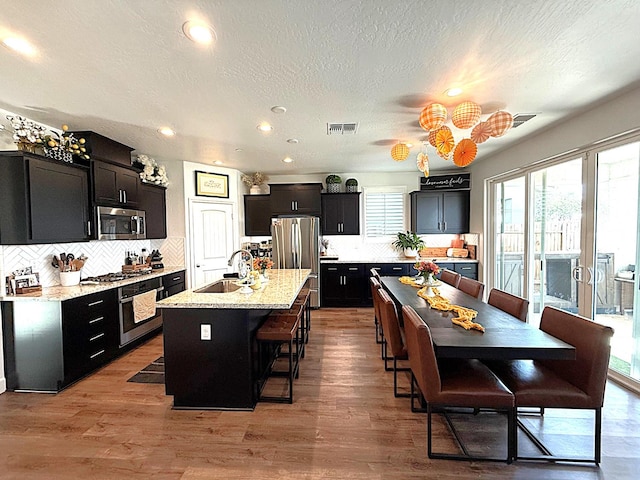 971 Dana Rd W, Madera, CA 93636 - kitchen featuring stainless steel appliances, decorative backsplash, a kitchen breakfast bar, recessed lighting, and wood finished floors
