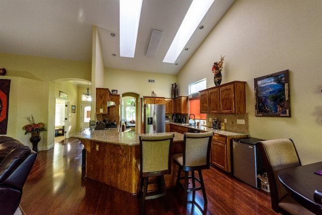 9930 N Rowell Ave, Fresno, CA 93720 - kitchen featuring stainless steel refrigerator with ice dispenser, arched walkways, dark wood-type flooring, a breakfast bar area, and high vaulted ceiling
