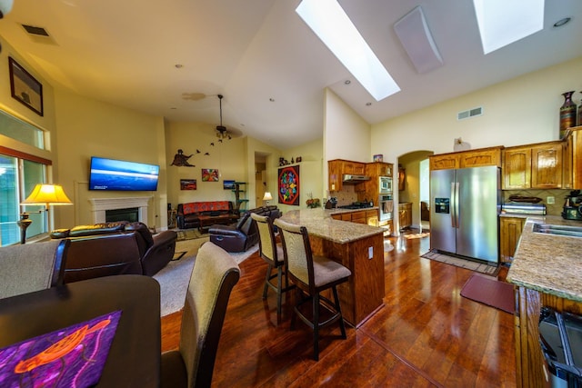 9930 N Rowell Ave, Fresno, CA 93720 - kitchen featuring stainless steel fridge with ice dispenser, a peninsula, open floor plan, dark wood-style floors, and high vaulted ceiling