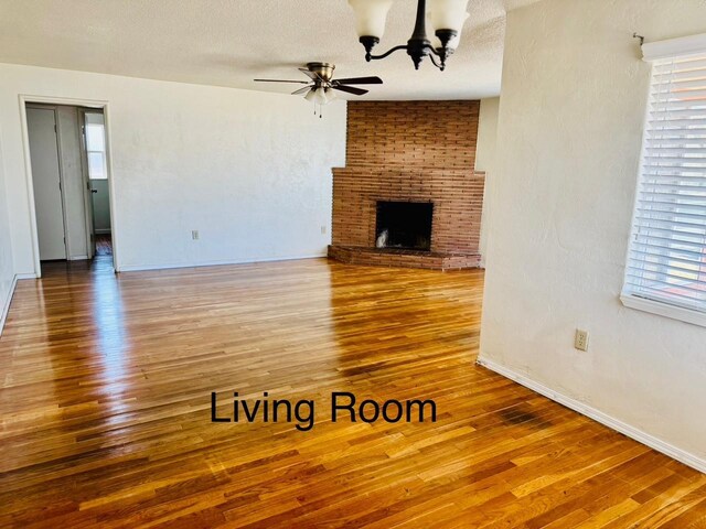 3646 E Dayton Ave, Fresno, CA 93726 - unfurnished living room with wood finished floors, a chandelier, a ceiling fan, and a brick fireplace