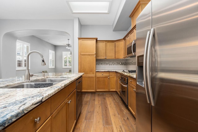 5313 W King Fisher Ln, Fresno, CA 93722 - kitchen featuring appliances with stainless steel finishes, dark wood-style flooring, brown cabinetry, and light stone counters