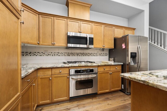 5313 W King Fisher Ln, Fresno, CA 93722 - kitchen with stainless steel appliances, light wood finished floors, backsplash, and light stone countertops