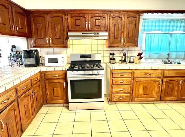 12420 S Chestnut Ave, Fresno, CA 93725 - kitchen with gas range, white microwave, under cabinet range hood, and tile countertops