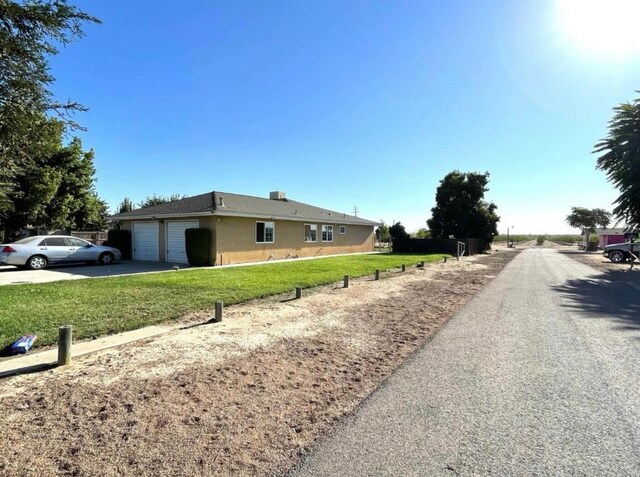 12420 S Chestnut Ave, Fresno, CA 93725 - view of side of home with a garage, driveway, a yard, and stucco siding