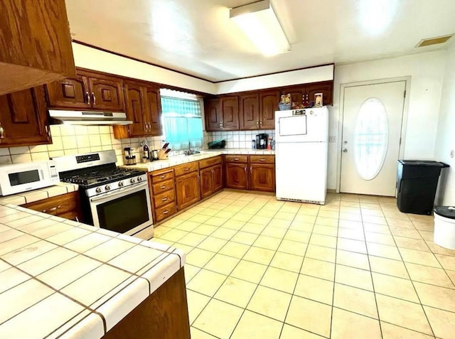 12420 S Chestnut Ave, Fresno, CA 93725 - kitchen with white appliances, under cabinet range hood, tile counters, and backsplash