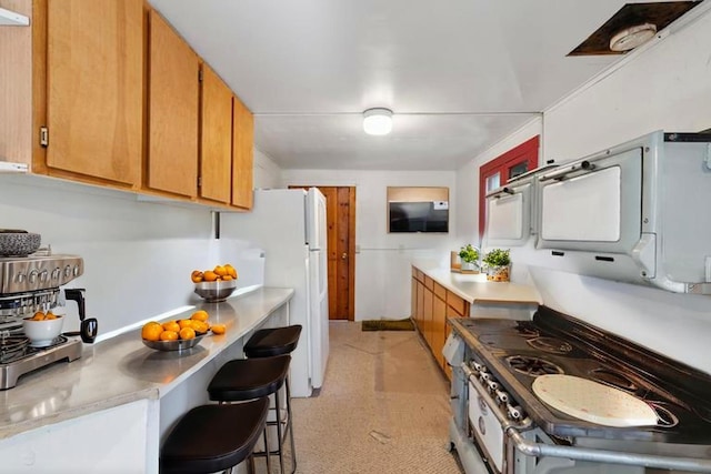 83634 Presidents Ln, Wilsonia, CA 93633 - kitchen with black gas range, freestanding refrigerator, light countertops, brown cabinetry, and light carpet