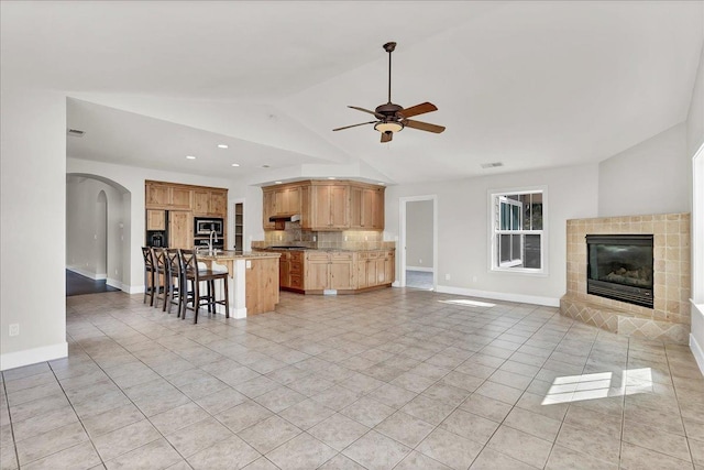 46453 Opah Dr, Ahwahnee, CA 93601 - living area with arched walkways, light tile patterned flooring, a ceiling fan, a fireplace, and lofted ceiling