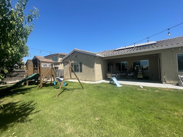 803 E Aretha Ave, Fowler, CA 93625 - rear view of house with a playground, a patio area, stucco siding, solar panels, and a tile roof
