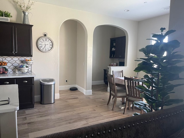 803 E Aretha Ave, Fowler, CA 93625 - kitchen featuring light countertops, light wood-type flooring, arched walkways, dark cabinets, and decorative backsplash