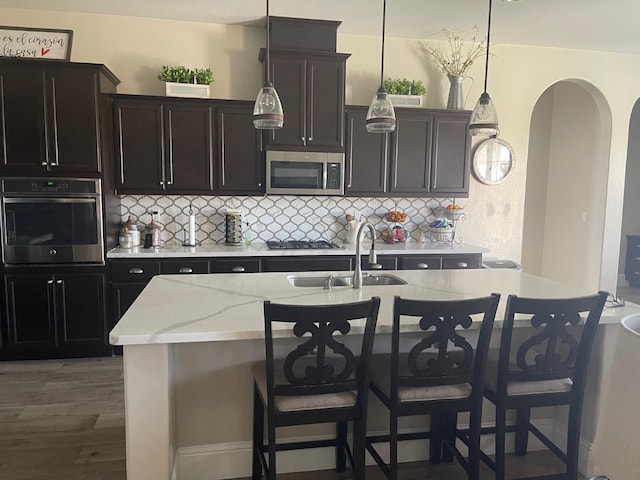 803 E Aretha Ave, Fowler, CA 93625 - kitchen with appliances with stainless steel finishes, backsplash, arched walkways, and a kitchen island with sink