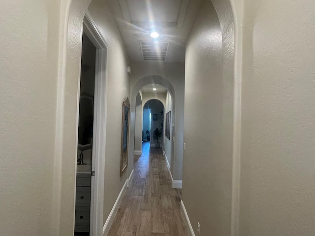 803 E Aretha Ave, Fowler, CA 93625 - hall featuring wood finished floors, arched walkways, and a textured wall