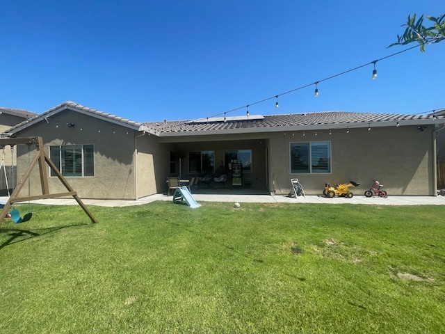 803 E Aretha Ave, Fowler, CA 93625 - rear view of property with stucco siding, a patio, roof mounted solar panels, a yard, and a tile roof