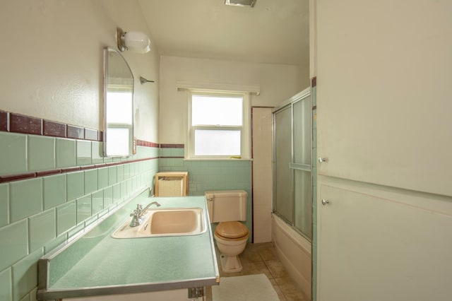 211 S 4th St, Fowler, CA 93625 - full bathroom featuring vanity, tile patterned flooring, shower / bath combination with glass door, tile walls, and a wainscoted wall