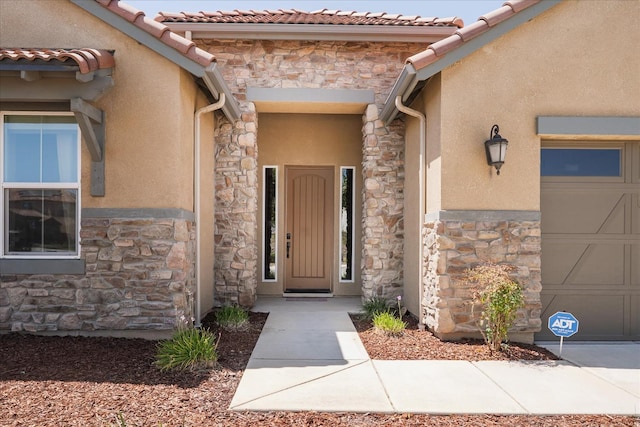 602 Pinnacle Dr W, Madera, CA 93636 - view of exterior entry with stone siding, a garage, and stucco siding