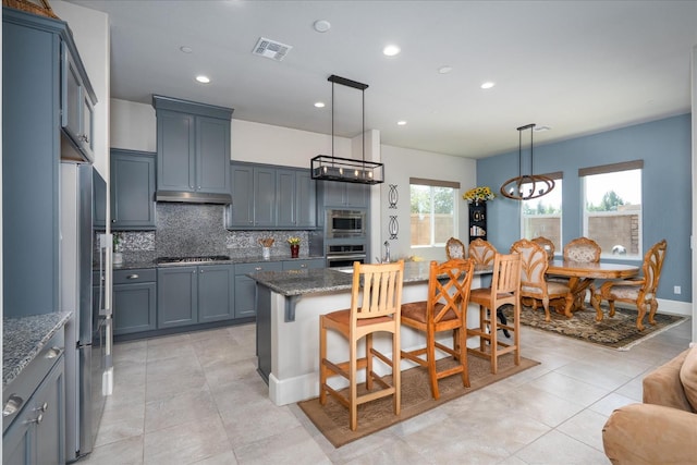 602 Pinnacle Dr W, Madera, CA 93636 - kitchen featuring appliances with stainless steel finishes, dark stone counters, backsplash, a kitchen breakfast bar, and a kitchen island