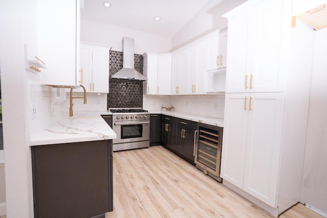 318 San Madele Ave, Coalinga, CA 93210 - kitchen featuring wall chimney exhaust hood, stainless steel stove, wine cooler, white cabinetry, and decorative backsplash