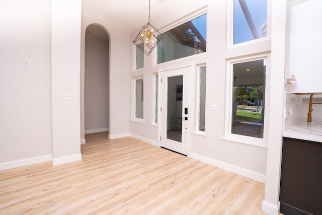 318 San Madele Ave, Coalinga, CA 93210 - unfurnished dining area featuring arched walkways, light wood-style flooring, and a high ceiling