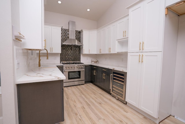 318 San Madele Ave, Coalinga, CA 93210 - kitchen featuring wall chimney exhaust hood, high end stainless steel range, beverage cooler, white cabinetry, and light stone counters