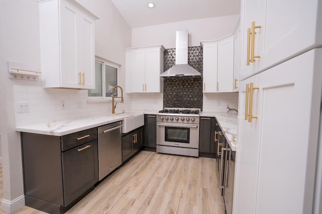 318 San Madele Ave, Coalinga, CA 93210 - kitchen featuring high end appliances, wall chimney range hood, white cabinetry, light stone counters, and light wood finished floors