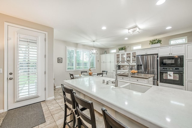 4626 N Arrow Ridge Way, Clovis, CA 93619 - kitchen featuring black appliances, recessed lighting, a kitchen bar, light tile patterned flooring, and glass insert cabinets