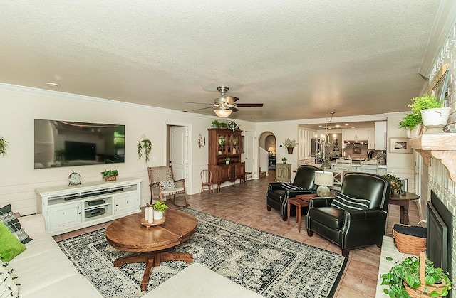 3012 Fairmont Ct, Madera, CA 93637 - living room featuring arched walkways, crown molding, a ceiling fan, a fireplace, and a textured ceiling