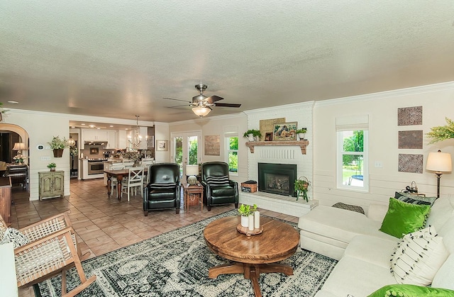3012 Fairmont Ct, Madera, CA 93637 - living room featuring crown molding, a ceiling fan, a brick fireplace, healthy amount of natural light, and a textured ceiling