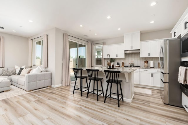 1275 Traverse Dr S, Madera, CA 93636 - kitchen with freestanding refrigerator, under cabinet range hood, recessed lighting, open floor plan, and a kitchen bar