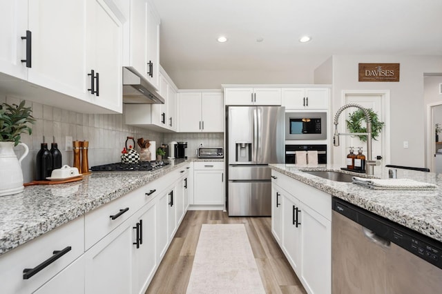 1275 Traverse Dr S, Madera, CA 93636 - kitchen featuring appliances with stainless steel finishes, under cabinet range hood, light wood-type flooring, white cabinets, and light stone countertops