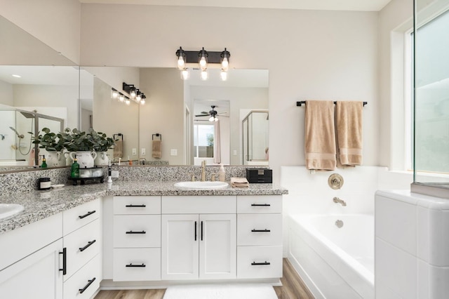 1275 Traverse Dr S, Madera, CA 93636 - bathroom featuring ceiling fan, double vanity, a shower stall, a garden tub, and wood finished floors