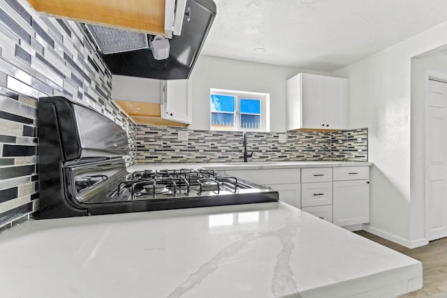124 E 4th St, Hanford, CA 93230 - kitchen with white cabinetry, tasteful backsplash, light stone countertops, and wood finished floors
