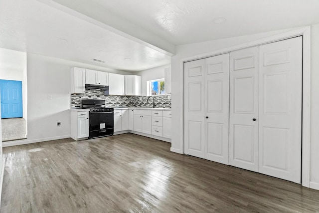 124 E 4th St, Hanford, CA 93230 - kitchen with black gas range, under cabinet range hood, wood finished floors, tasteful backsplash, and white cabinetry