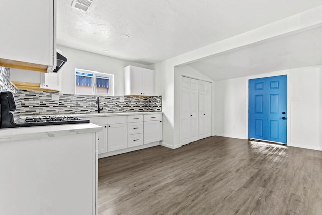 124 E 4th St, Hanford, CA 93230 - kitchen featuring decorative backsplash, light countertops, white cabinets, wood finished floors, and lofted ceiling