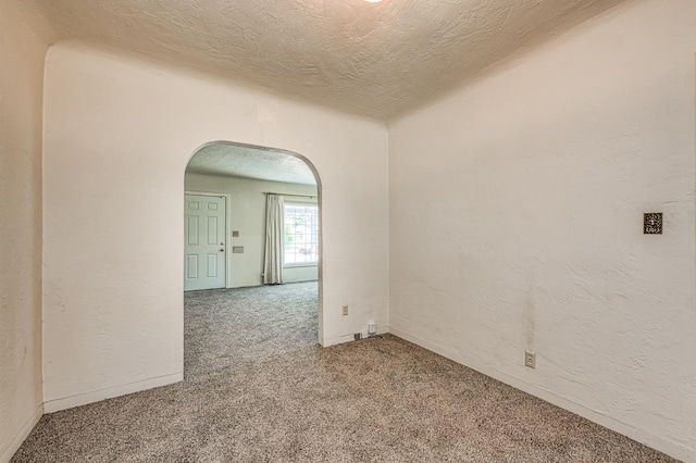 4740 E Washington Ave, Fresno, CA 93702 - carpeted spare room featuring arched walkways, a textured ceiling, and a textured wall