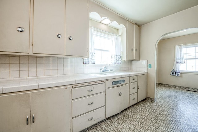 4740 E Washington Ave, Fresno, CA 93702 - kitchen featuring decorative backsplash, arched walkways, and tile counters