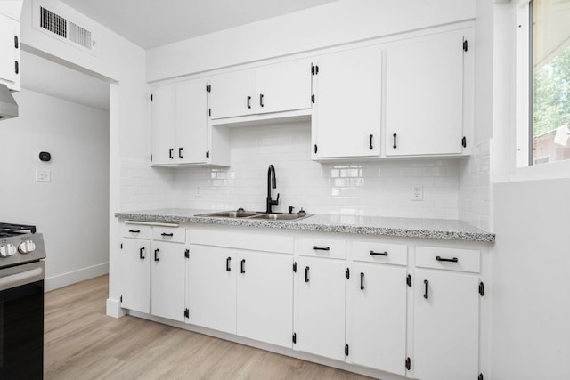 145 W Atchison Ave, Fresno, CA 93706 - kitchen with stainless steel range, backsplash, white cabinetry, light wood-style floors, and light stone counters