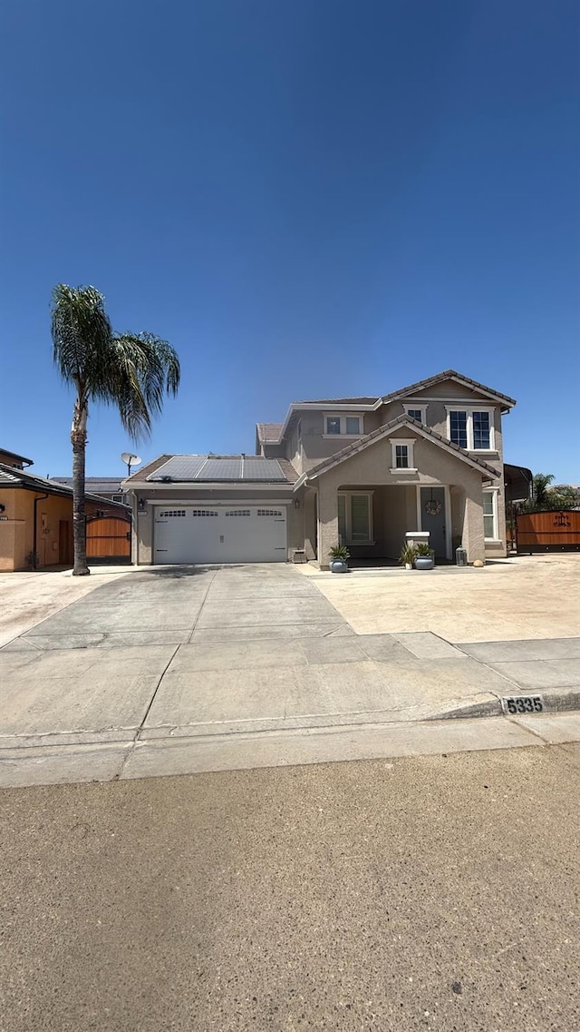 5335 E Hoxie Ave, Fresno, CA 93725 - view of front of home with an attached garage, driveway, stucco siding, and solar panels