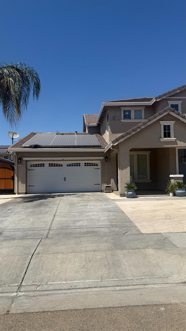 5335 E Hoxie Ave, Fresno, CA 93725 - view of front of home featuring stucco siding, an attached garage, driveway, roof mounted solar panels, and a tile roof