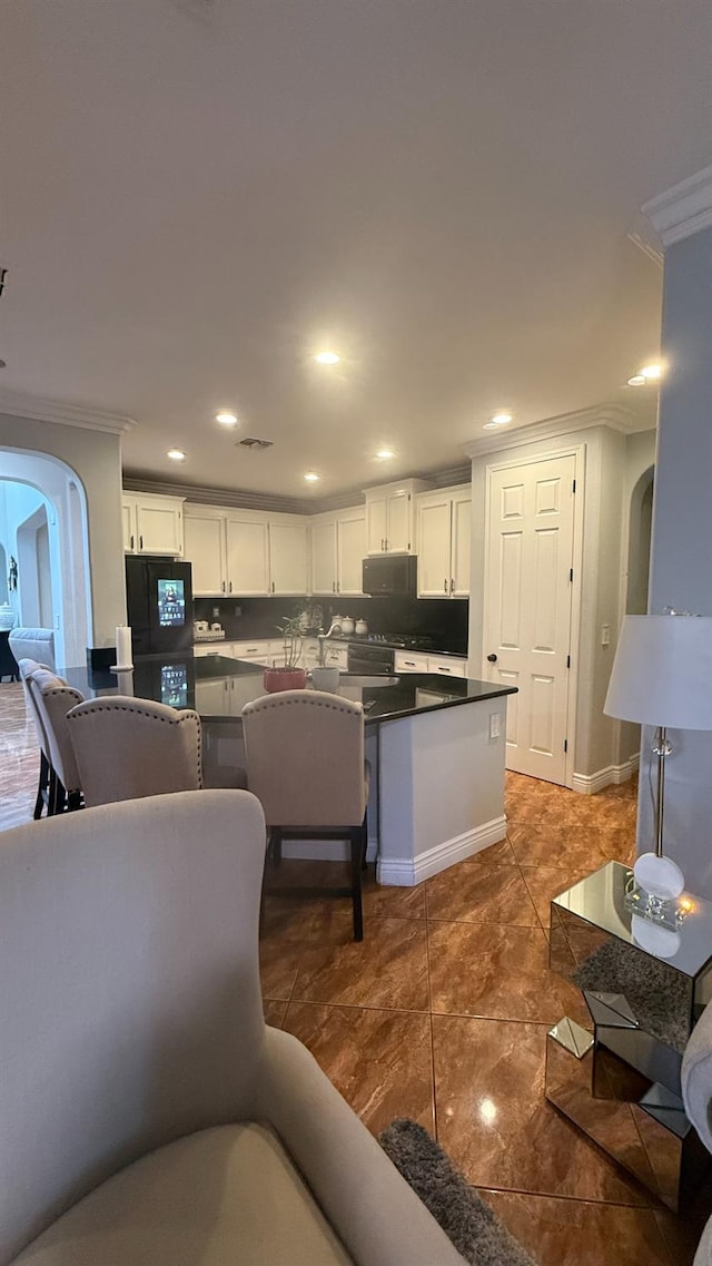 5335 E Hoxie Ave, Fresno, CA 93725 - kitchen featuring crown molding, arched walkways, dark countertops, black appliances, and white cabinetry