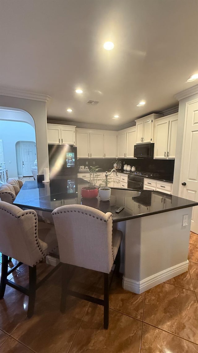 5335 E Hoxie Ave, Fresno, CA 93725 - kitchen featuring black microwave, dark countertops, freestanding refrigerator, crown molding, and white cabinetry