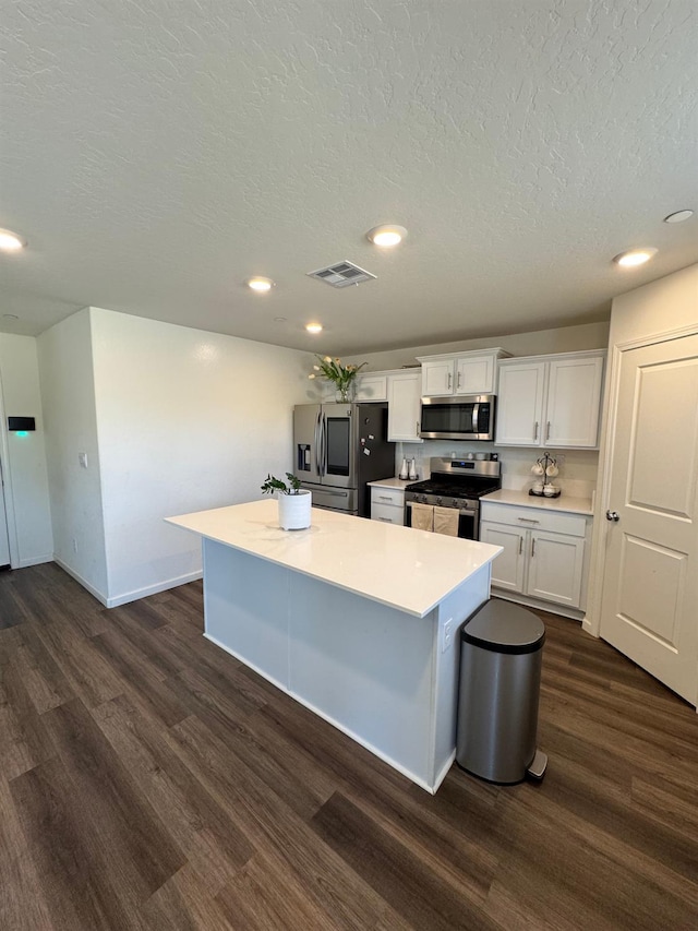 1905 George Ave, Sanger, CA 93657 - kitchen with appliances with stainless steel finishes, dark wood finished floors, a center island, white cabinetry, and a textured ceiling